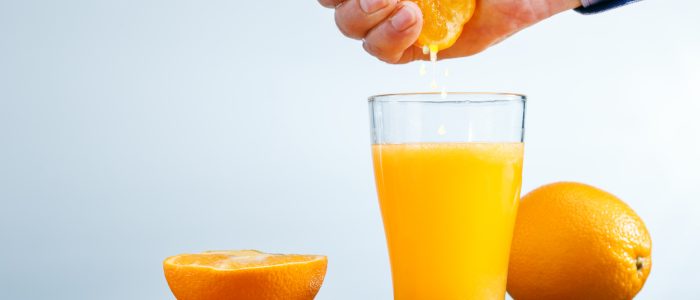 Man making healthy organic orange juice in kitchen. Copy space. Vitamin drink.